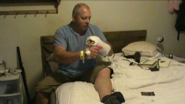 Bruno Rocuba ngồi trên giường, cầm một khẩu súng đồ chơi để minh họa cho cảnh sát những gì đã xảy ra.