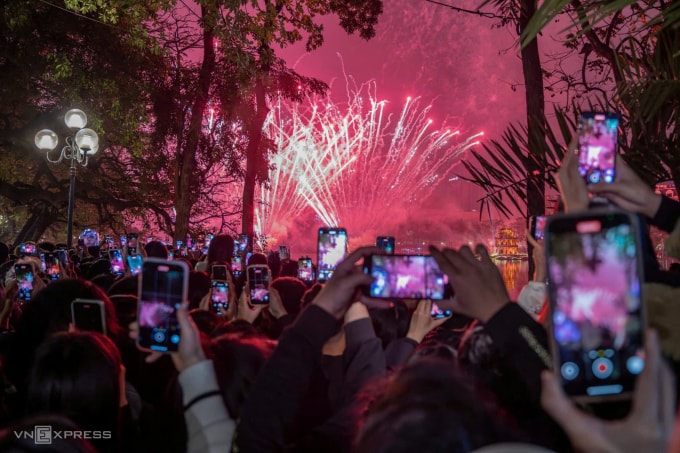 Người dân dùng điện thoại ghi lại khoảnh khắc bắn pháo hoa chào mừng Tết Dương lịch 2026 tại Hồ Gươm. Ảnh: Giang Huy