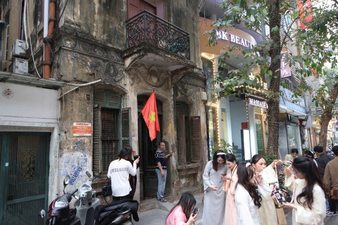 Ông Phùng Tiến Vinh đứng trước cửa nhà nhìn đám đông đứng kín lối ra, vào nhà trên phố Nguyễn Trường Tộ, phường Ba Đình, chiều 4/2. Ảnh: M.N