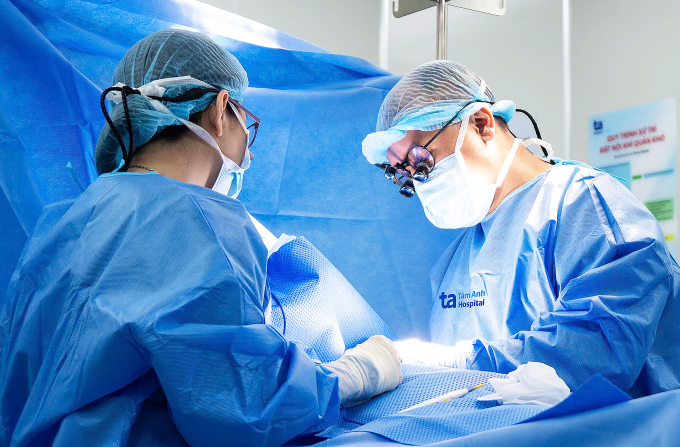 Bác sĩ Trọng (phải) phẫu thuật lấy kén bã đậu cho bé Liên. Ảnh: Trung Vũ