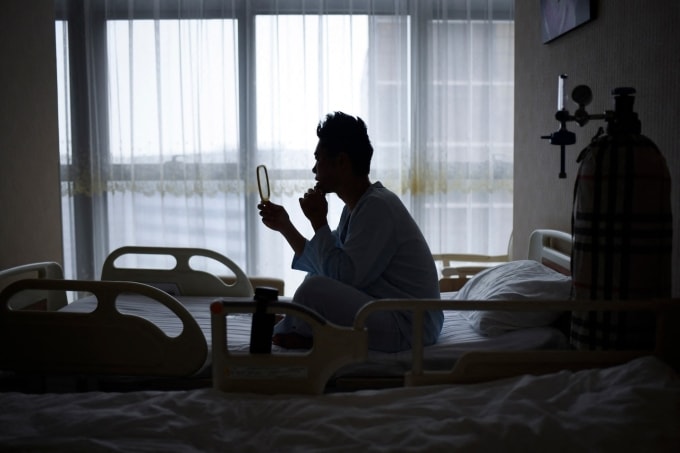 Bệnh nhân Xia Shurong soi gương sau ca phẫu thuật thẩm mỹ tại một phòng khám ở Bắc Kinh hồi tháng 7/2021. Ảnh: AFP