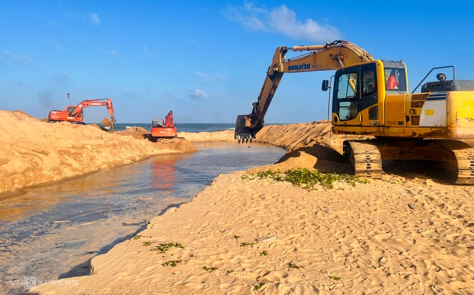 Cửa biển Lý Hòa bị cát bịt kín được chính quyền huy động máy múc đào cát mở cửa mới để nước thoát. Ảnh: Đắc Thành