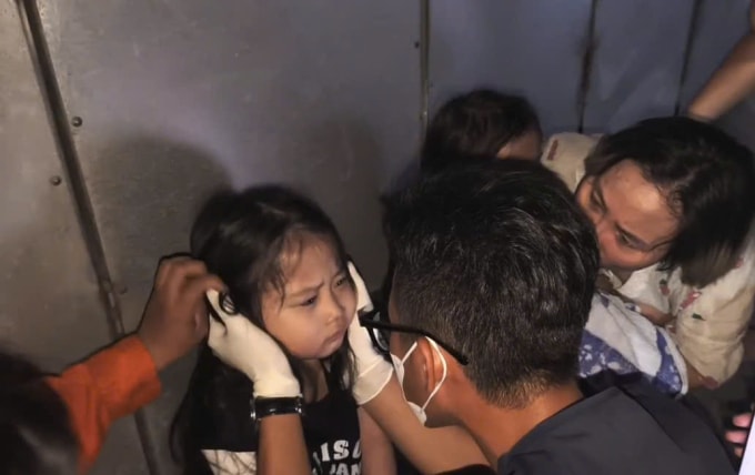 Nhân viên y tế kiểm tra sức khỏe của gia đình được giải cứu khỏi nhà cháy. Ảnh: Minh Bằng