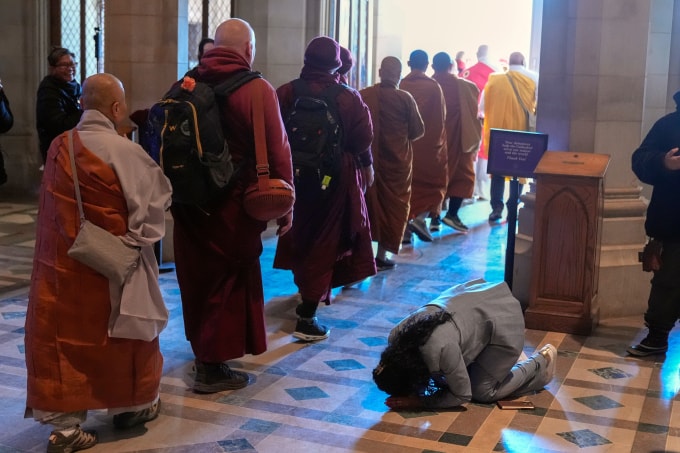 Một phụ nữ quỳ trước đoàn nhà sư vừa tới Washington, chuẩn bị thăm Nhà thờ Quốc gia, ngày 10/2. Ảnh: AP