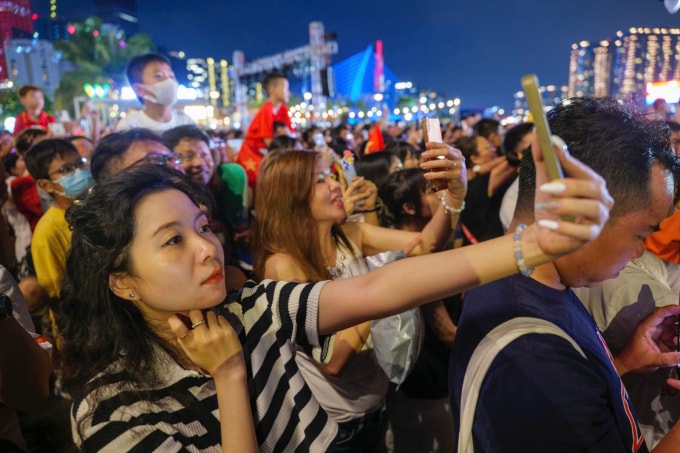 Người dân dùng điện thoại quay phim, chụp hình khoảnh khắc pháo hoa rực sáng trên sông Sài Gòn. Ảnh: Hoàng Việt