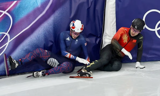 Treacy (trái) và Liu sau khi bị ngã ở chung kết 1.500m trượt băng tốc độ short-track, Olympic mùa Đông 2026 tại Milano, Italy tối 14/2/2026. Ảnh: EPA
