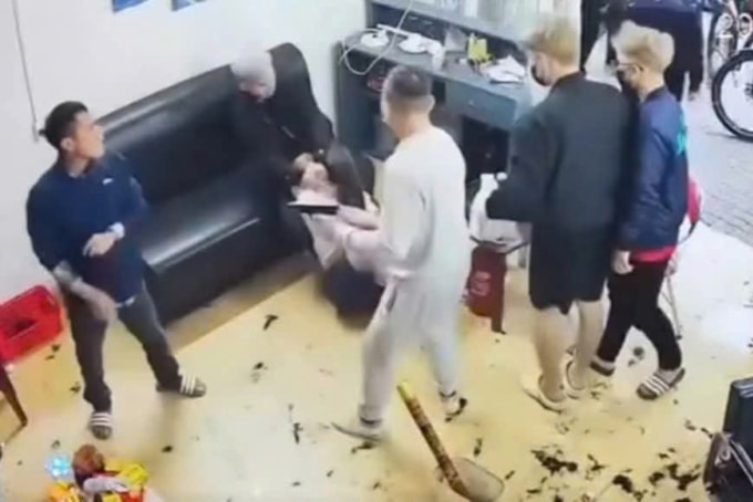 Long (áo trắng) cầm súng đe dọa và cùng đồng phạm đánh đập chủ tiệm cắt tóc nợ tiền mình. Ảnh: Cắt từ video