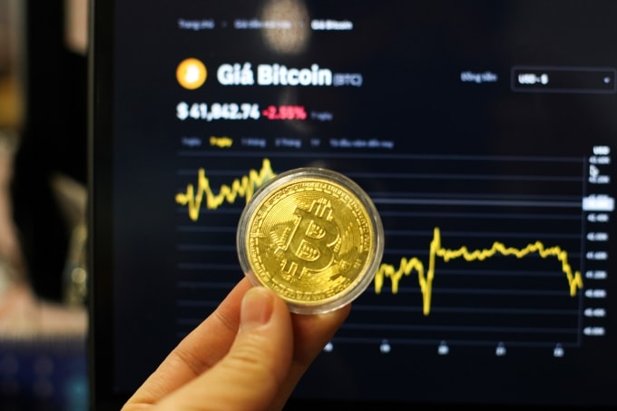 Đồng xu biểu tượng Bitcoin trước biểu đồ diễn biến giá. Ảnh: Khương Nha