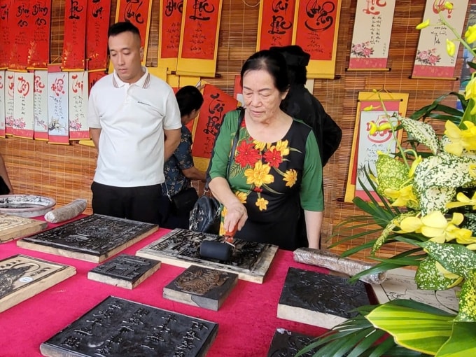 Du khách trải nghiệm khắc dấu bản mộc ở chùa Côn Sơn. Ảnh: Lê Tân