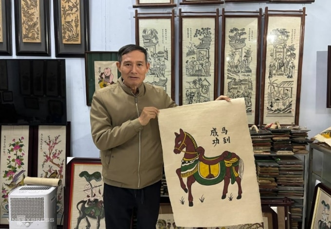 Nghệ nhân Ưu tú Nguyễn Hữu Quả bên bức tranh ‘Mã đáo thành công’- dòng tranh được ưa chuộng mùa Tết Bính Ngọ 2026 . Ảnh: Việt An