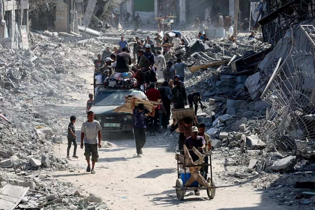 Người dân Palestine đi bộ qua đống đổ nát sau khi lực lượng Israel rút khỏi khu vực, sau khi Israel và Hamas đạt được thỏa thuận ngừng bắn ở Gaza, tại Khan Younis, phía nam Dải Gaza, ngày 10/10. (Ảnh: Reuters)