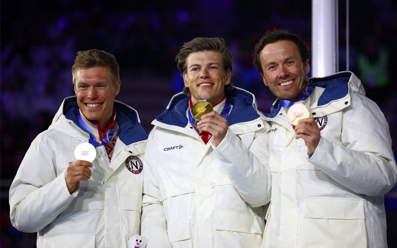 VĐV Na Uy Johannes Høsflot Klæbo giành HCV ăn mừng trên bục trao giải sau khi chiến thắng nội dung 50km xuất phát đồng hàng cổ điển nam, cùng HCB Martin Løwstrøm Nyenget (Na Uy) và HCĐ Emil Iversen (Na Uy).