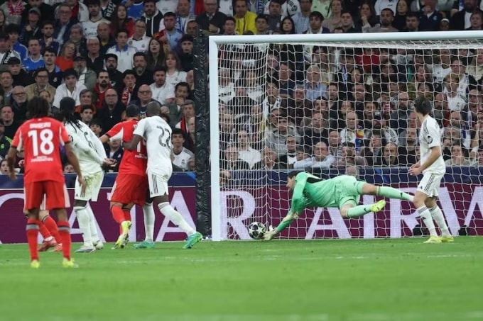 Courtois (áo xanh) cứu thua ở phút 37 trận lượt về vòng play-off Champions League, Real 2-1 Benfica tối 25/2. Ảnh: EPA