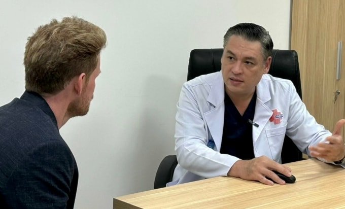 Bác sĩ Lệnh Hùng trao đổi cùng bệnh nhân người Mỹ sau ca mổ thành công. Ảnh: Trần Nhung