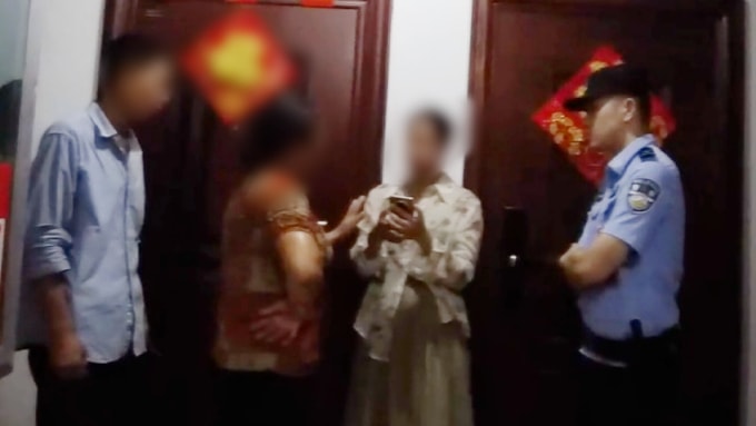 Trần (áo trắng) nhận lại điện thoại đánh mất từ bà Lý dưới sự chứng kiến của cảnh sát. Ảnh: QQ