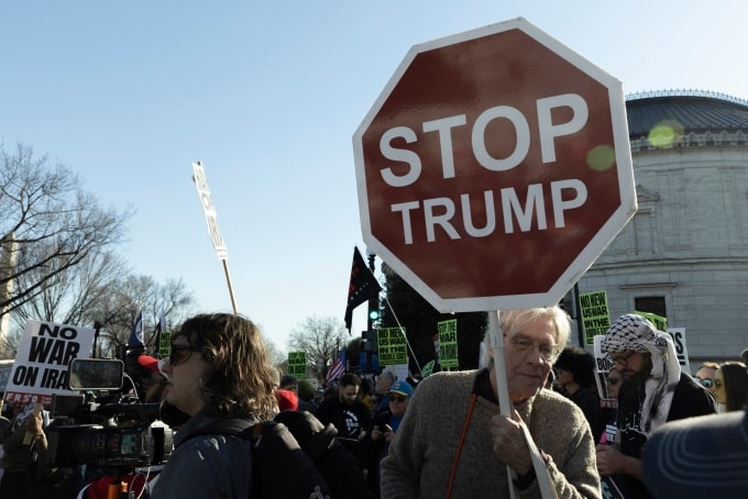 Người đàn ông cầm biểu ngữ đề chữ Hãy ngăn ông Trump tại khu vực gần Nhà Trắng, thủ đô Washington, ngày 28/2. Ảnh: AFP