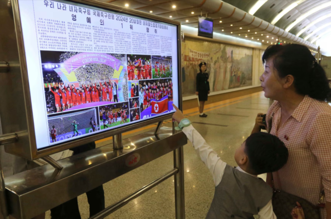 Người dân Triều Tiên theo dõi tin tức về đội tuyển U20 nữ, trên một màn hình tại ga Kaeson, Bình Nhưỡng. Ảnh: AP
