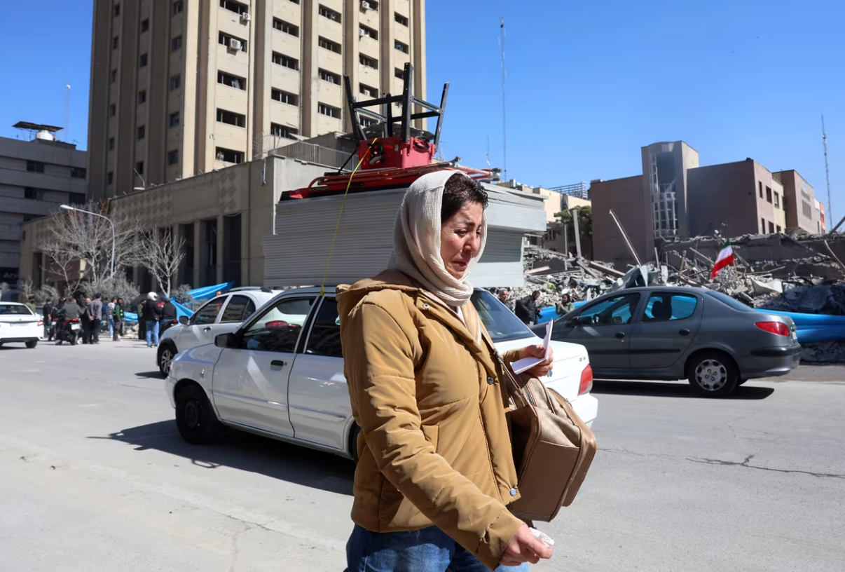 Người phụ nữ Iran bày tỏ sự đau buồn khi đi bộ gần một tòa nhà bị hư hại quanh Quảng trường Ferdowsi sau cuộc không kích ở trung tâm Tehran, Iran. (Ảnh: Shutterstock)