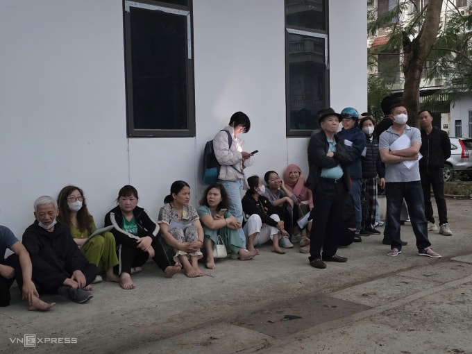 Phụ huynh trú mưa ở đối diện cổng trường THPT Phan Bội Châu, 6h sáng 3/3. Ảnh: Thanh Hằng