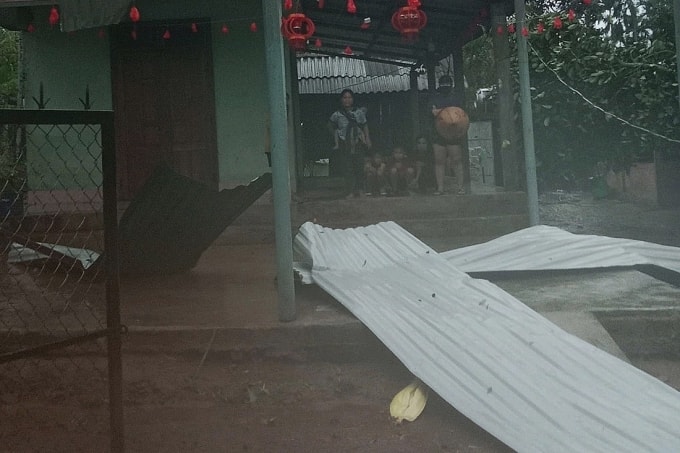 Một gia đình người HRe nhìn ra những mảng tôn bị bay xuống trong cơn lốc. Ảnh: Thành Minh