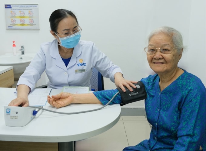 Bà Hột được bác sĩ khám sàng lọc trước khi tiêm ngừa cúm, phế cầu. Ảnh: Hoàng Dương