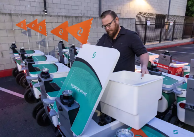 Một nhân viên kiểm tra robot giao hàng tại nhà kho của Serve Robotics. Ảnh: Los Angeles Times