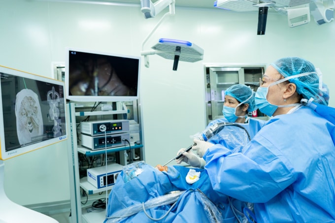 Giáo sư Chung Thủy (ngoài cùng phải) quan sát màn hình nội soi và màn hình hệ thống định vị AI để phẫu thuật cho người bệnh. Ảnh: Bệnh viện Đa khoa Tâm Anh