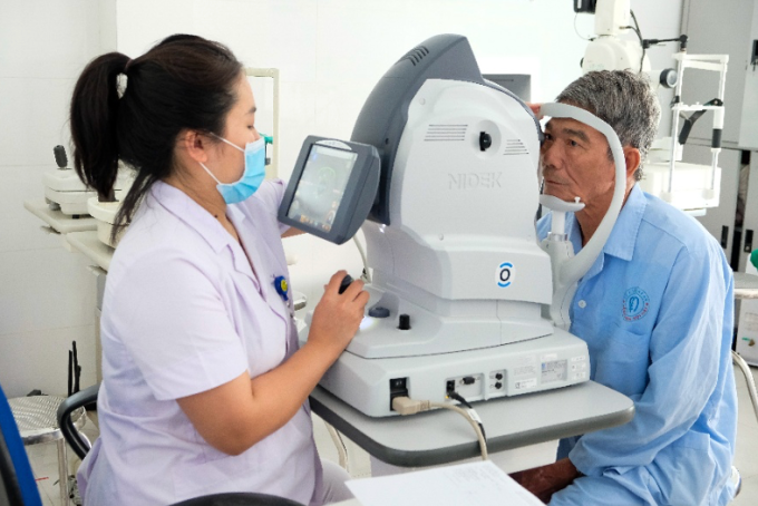 Nhân viên y tế kiểm tra mắt cho người bệnh bằng máy chụp ảnh đáy mắt không huỳnh quang. Ảnh: Roche