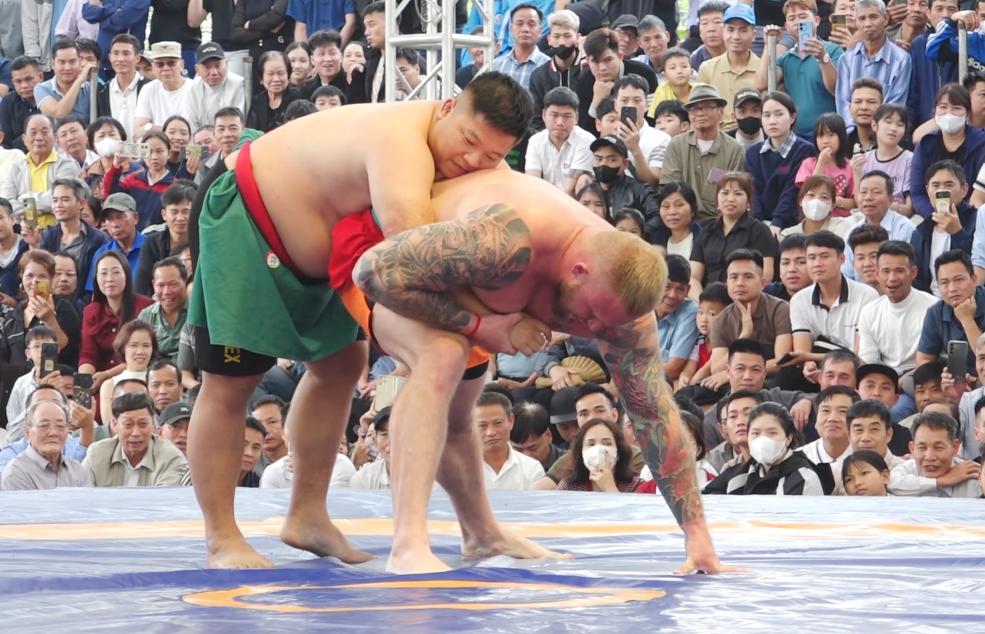 Đô vật Nguyễn Thế Cử luồn ra phía sau, kiểm soát phần lưng của Alex.