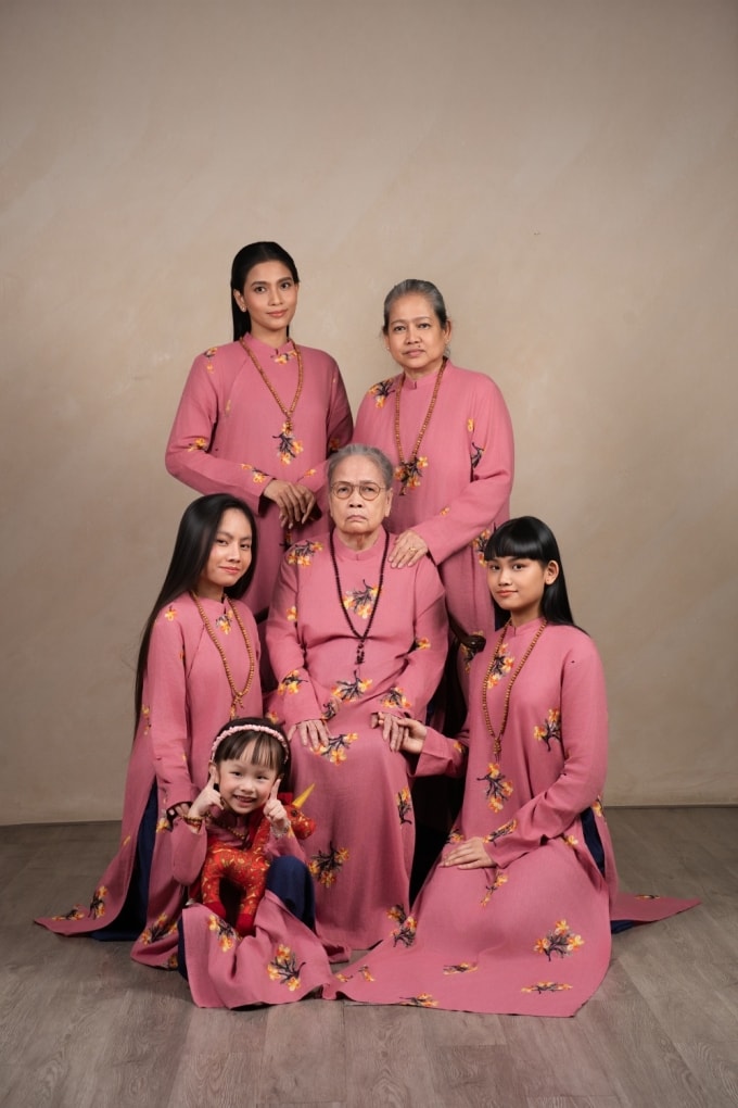 Trương Thị May (trái, hàng sau cùng) mặc áo dài họa tiết hoa chụp ảnh cùng gia đình. Trong ảnh gồm bà ngoại (ngồi giữa hàng hai), mẹ ruột, hai em và con gái của cô.