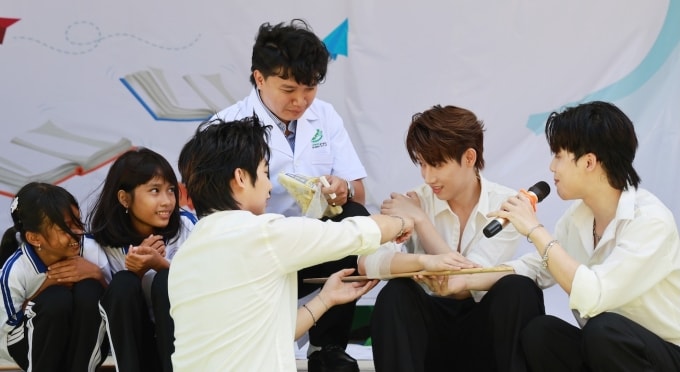 Các ca sĩ Hồ Đông Quan, LighT, SWAN (ngồi bên phải) và học sinh thực hành sơ cứu trong tình huống giả định một người bị tai nạn gãy tay, dưới sự hướng dẫn của bác sĩ Phạm Thái Ngọc Long (mặc áo blouse). Ảnh: Đức Đồng