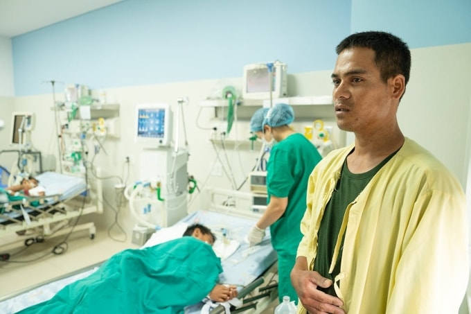 Anh Hồ Văn Mía bên giường bệnh nơi hai con đang được chăm sóc đặc biệt nghi do ngộ độc botulinum. Ảnh: Nguyễn Đông