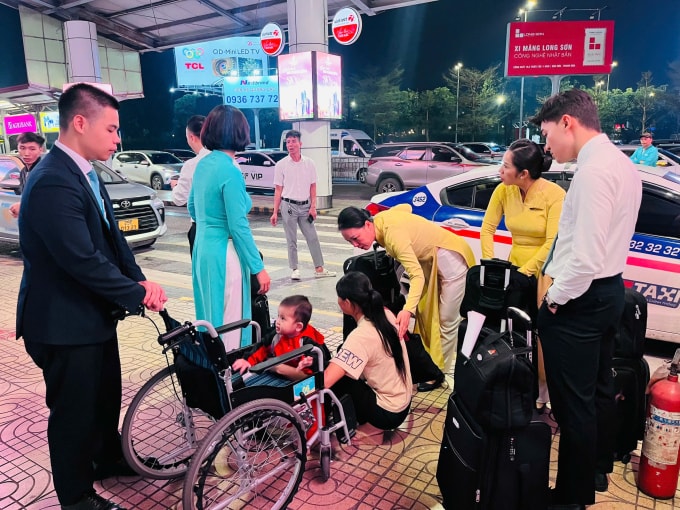 Chị Nông Thị Hà (áo màu be) và con trai 2 tuổi được tổ tiếp viên hàng không của hãng hàng không Vietnam Airline đưa ra cổng ga tại sân bay Nội Bài (Hà Nội), sau gọi taxi để lên xe khách về Cao Bằng, tối 26/2. Ảnh: Phạm Thu Hà