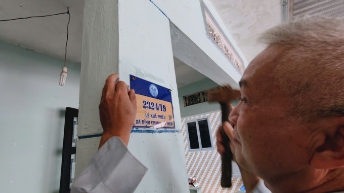 Ông Hậu lắp số nhà mới được UBND xã Bình Chánh cấp thay cho bảng số cũ A12/36 không có tên đường, ngày 11/3. Ảnh: Đình Văn