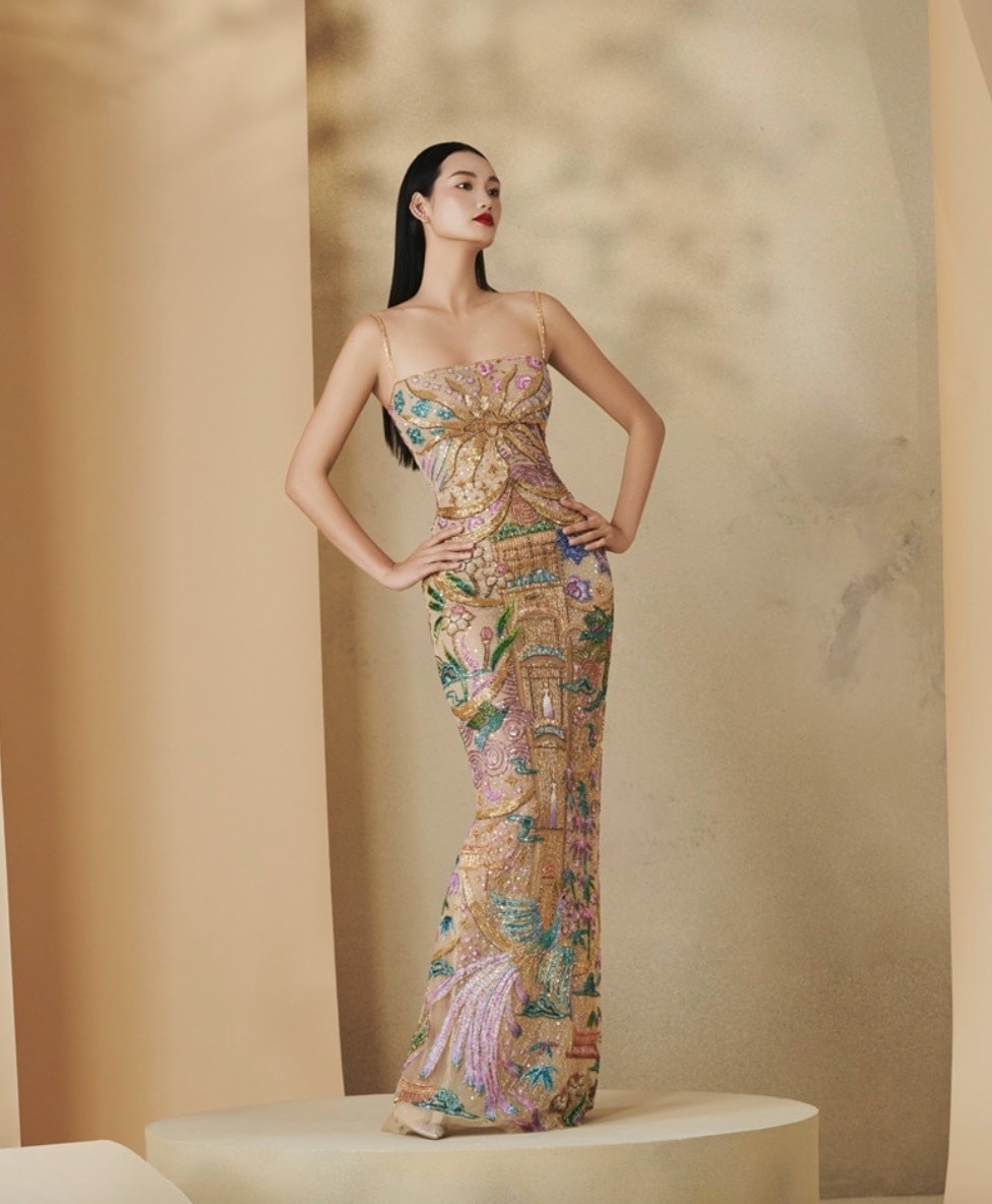 Người đẹp diện chiếc đầm dài ôm sát thêu họa tiết cố đô Huế đính kết thủ công tỉ mỉ, với hình ảnh lầu son, hoa lá, chim muông xứ Huế được thêu tay bằng chỉ màu rực rỡ trên nền lụa vàng.