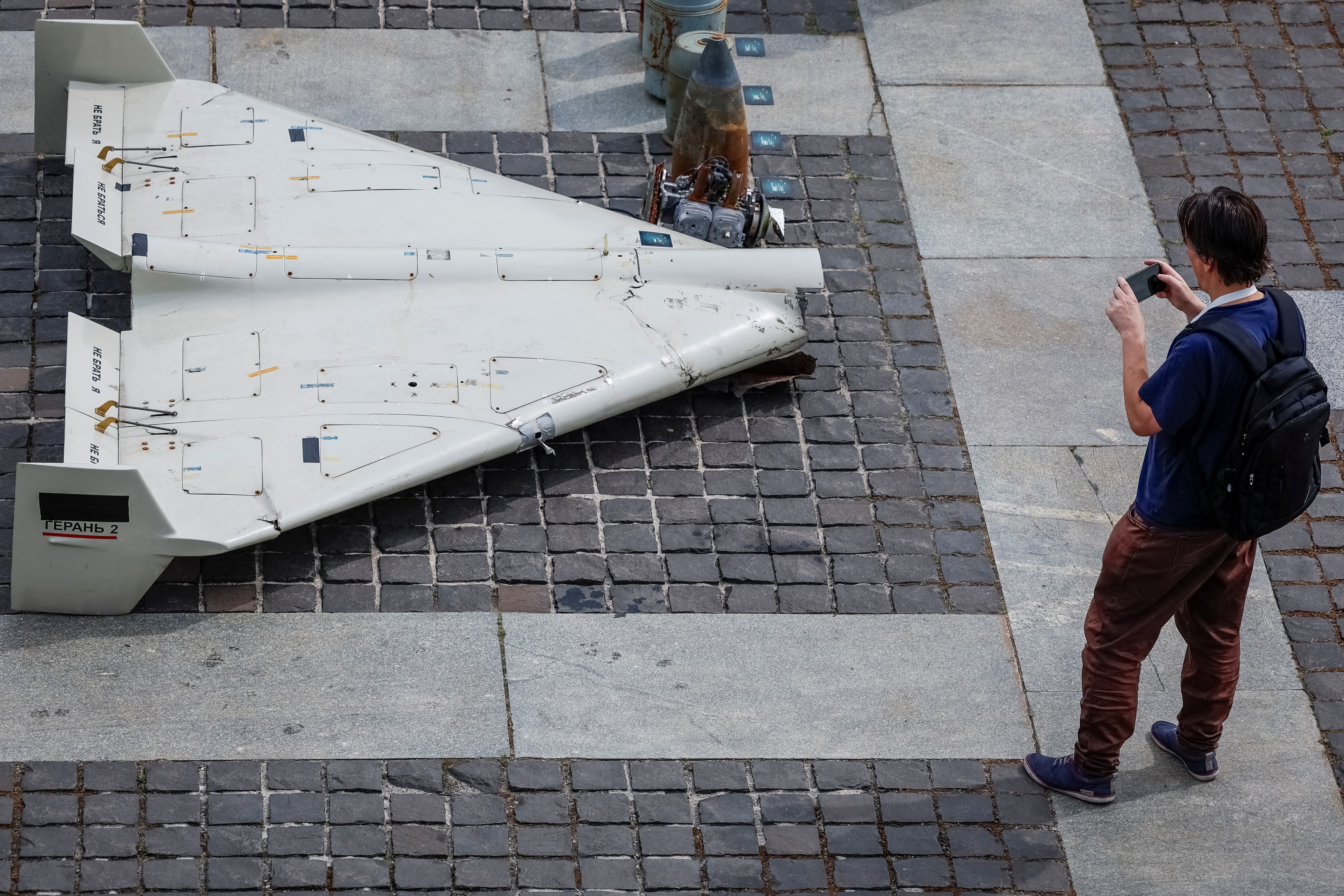 Một khách tham quan triển lãm chụp ảnh các bộ phận của máy bay không người lái (UAV) Shahed-131/136 do Iran sản xuất, từng được phóng vào lãnh thổ Ukraine trong bối cảnh Nga tấn công nước này, tại Kiev, Ukraine, ngày 27/6/2025. (Ảnh: REUTERS/Alina Smutko)