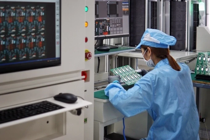 Nhân viên một nhà máy sản xuất đồ điện tử đang kiểm tra một bảng mạch vừa hoàn thành. Ảnh: Lưu Quý