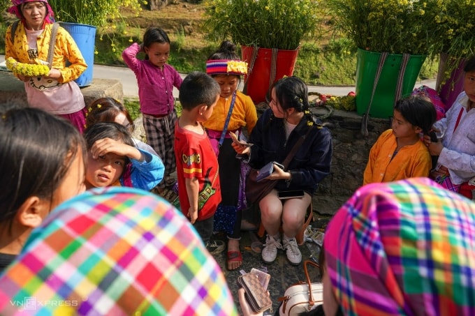 Du khách cho tiền trẻ em sau khi được tết tóc ở dốc Thẩm Mã vào tháng 3. Ảnh: Hoàng Giang