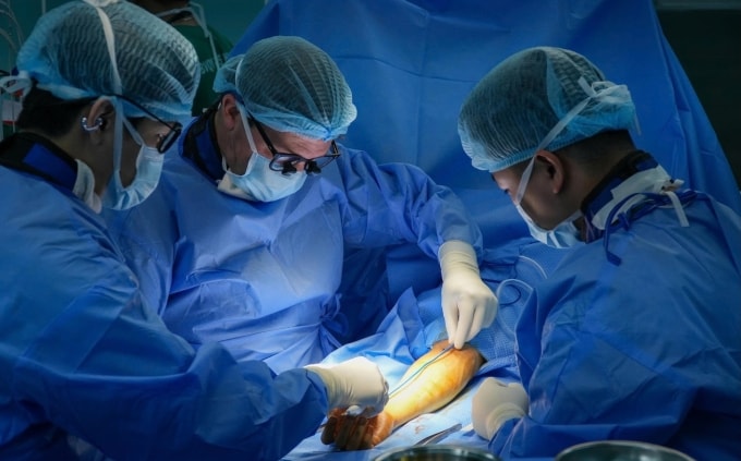 Các bác sĩ Bệnh viện Quân y 175 và chuyên gia Mỹ phẫu thuật bàn tay cho bệnh nhân, ngày 19/3. Ảnh: Bệnh viện cung cấp