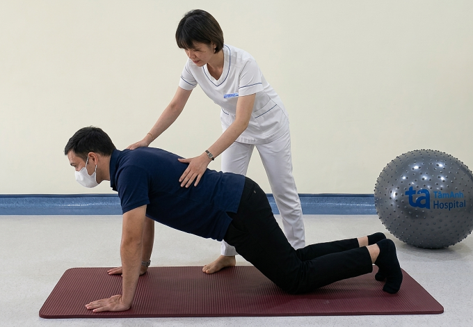 Chuyên gia vật lý trị liệu hướng dẫn người bệnh tập hít đất gối chạm sàn. Ảnh: Phòng khám Đa khoa Tâm Anh Cầu Giấy
