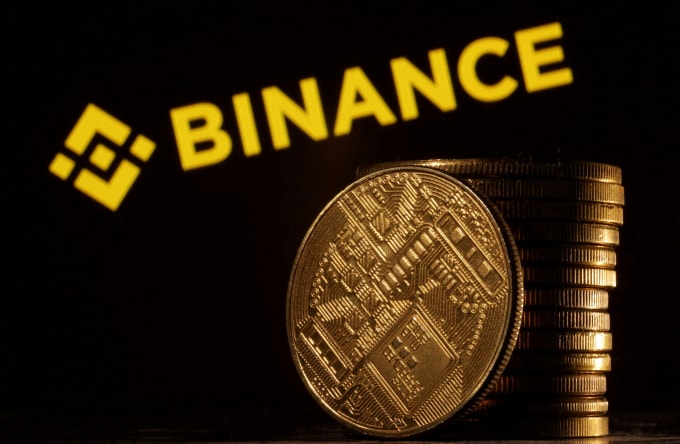 Các đồng xu biểu trưng cho tiền số được đặt trước logo Binance. Ảnh: Reuters