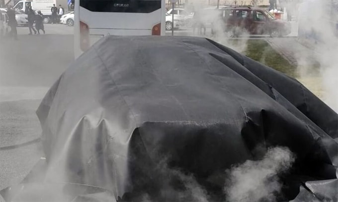 Tấm chăn lớn phủ kín chiếc xe điện cháy. Ảnh: Avrupa Haberler