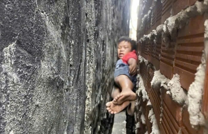 Bé trai kẹt giữa 2 bức tường. Ảnh: Thái Hà