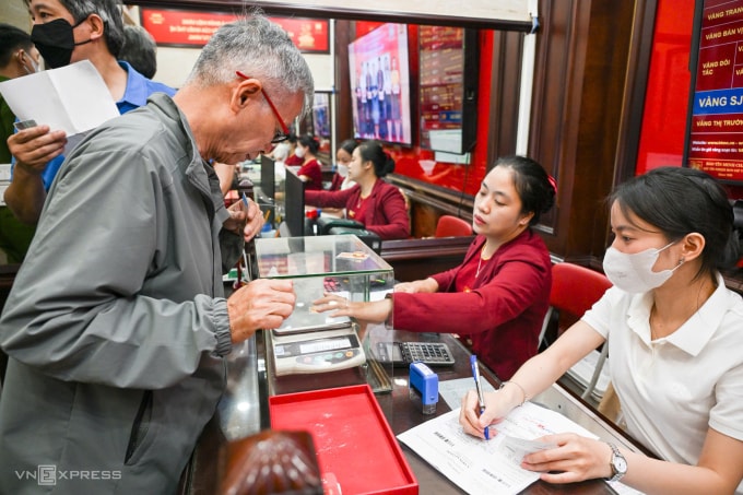 Khách tới giao dịch tại cửa hàng Bảo Tín Minh Châu trên đường Trần Nhân Tông trưa 26/3, một ngày sau khi thương hiệu tạm đóng vì bị kiểm tra. Ảnh: Giang Huy