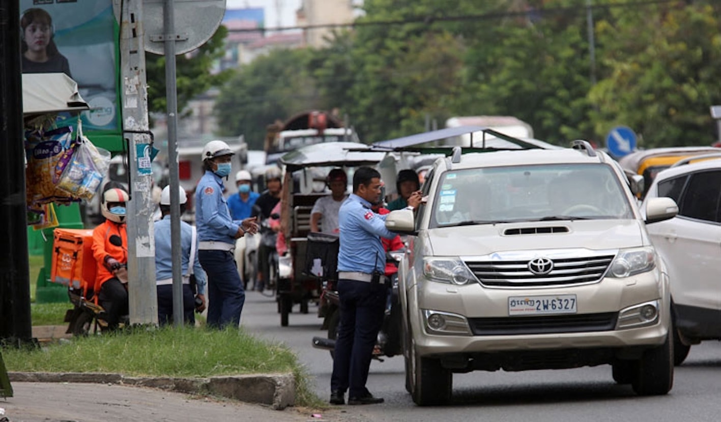 Một cảnh sát giao thông ra hiệu dừng xe và lập biên bản đối với một người lái xe trên đại lộ Preah Sihanouk tại thủ đô.