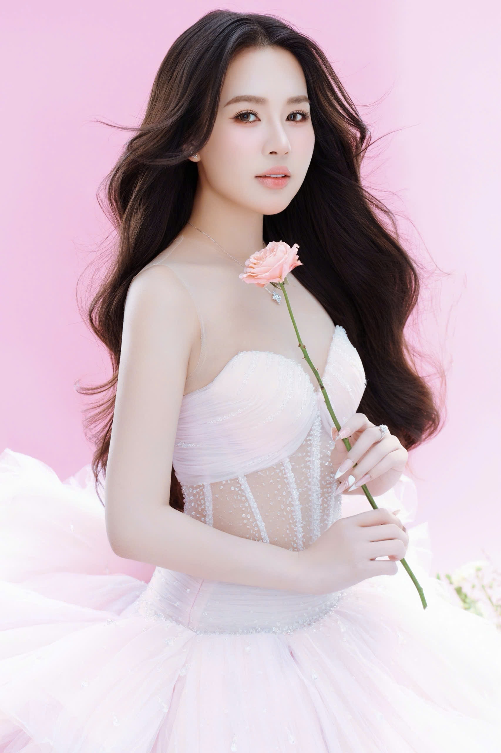 Hà Trang lựa chọn lối trang điểm trong veo, nhấn nhẹ vào đôi mắt và làn môi hồng tự nhiên, giúp tôn lên gương mặt thanh tú, đường nét hài hòa. Mái tóc dài uốn nhẹ, buông xõa tự nhiên càng làm nổi bật vẻ dịu dàng, nữ tính.