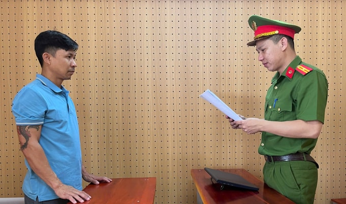 Nghi can Đoàn (góc trái) nghe cảnh sát đọc lệnh khởi tố. Ảnh: Công an cung cấp