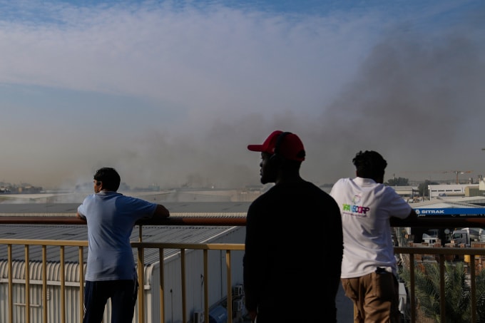Người đi đường nhìn khói bốc lên sau vụ đánh chặn ở khu công nghiệp Al Quoz ở Dubai, UAE ngày 13/3. Ảnh: AP