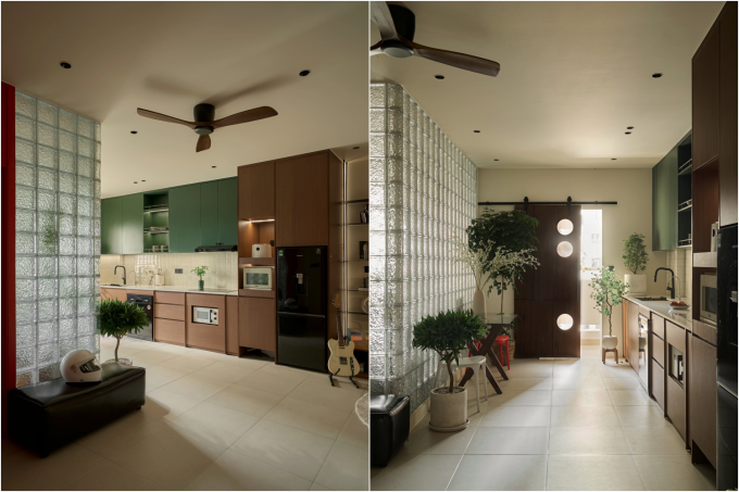 Căn hộ 70 m2 phong cách Mid-century Modern tại TP HCM sau cải tạo sử dụng mảng tường gạch kính trong suốt cao sát trần thay thế vách ngăn cũ giữa phòng ngủ master và khu sinh hoạt chung. Bề mặt gạch kính dạng sóng khuếch tán ánh sáng tự nhiên từ phòng ngủ sang khu bếp, vốn là vùng tối nhất trong mặt bằng cũ, đồng thời vẫn giữ được ranh giới không gian giữa hai khu vực. Ảnh;