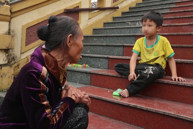 Bà Hồ Thị Hoan, mẹ Cường, ngồi trông cháu ở sân tòa. Ảnh: Hùng Lê